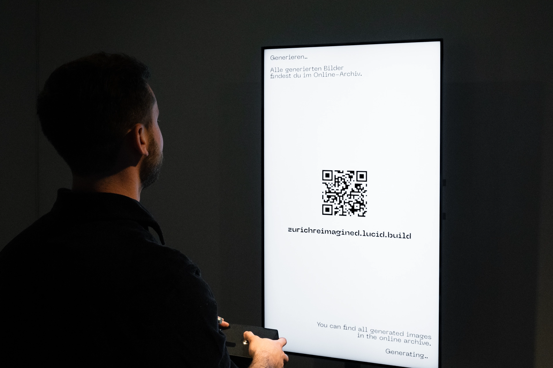 Ein Besucher wartet darauf, dass sein Bild generiert wird. Er steht vor dem grossen Bildschirm mit den Händen auf der Interaktionsbox.
