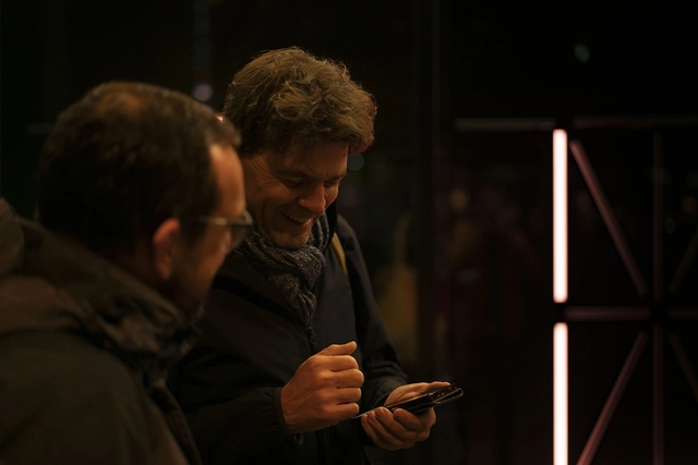 Zwei Besucher benutzen ein Smartphone um einen Buchstaben auf der Installation zu ändern.